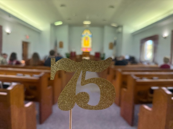 Seventy five in glittering gold text with blurred sanctuary background